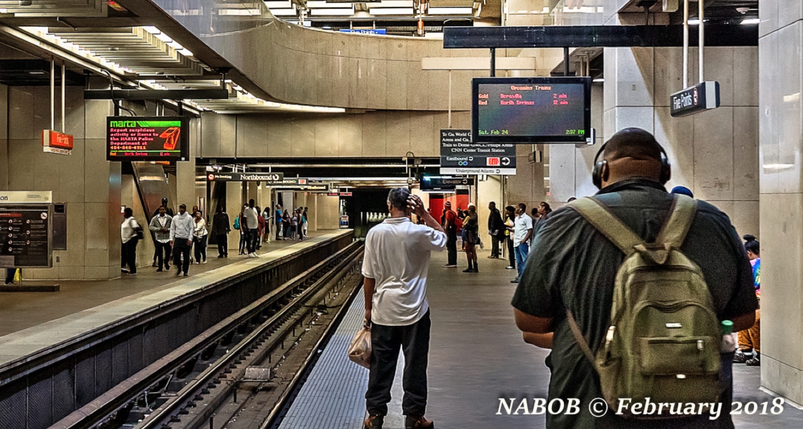 A crowded MARTA platform with riders reading the old departure boards